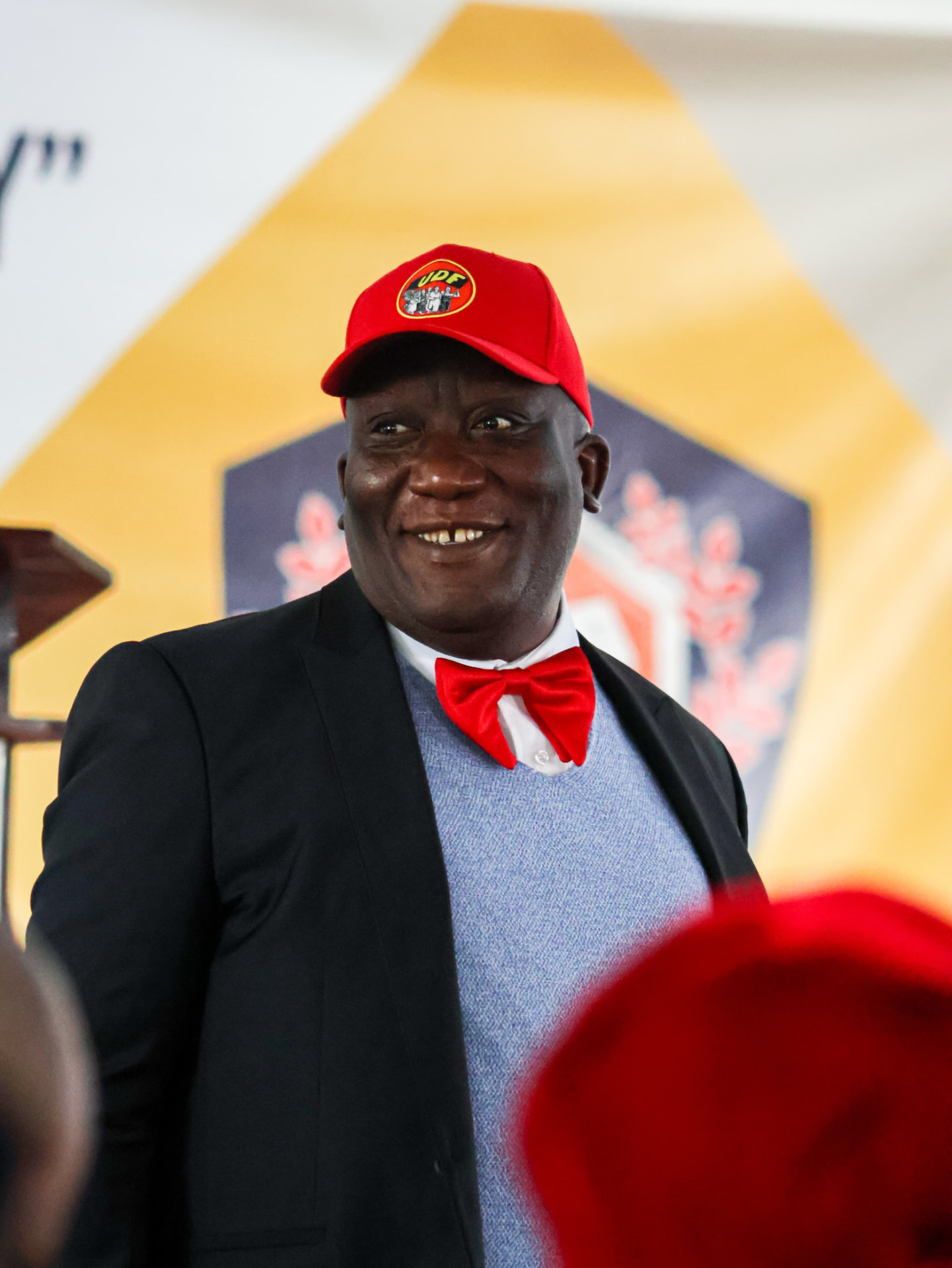 Bishop Mogodiri smiling in a red bow tie and cap at a community event