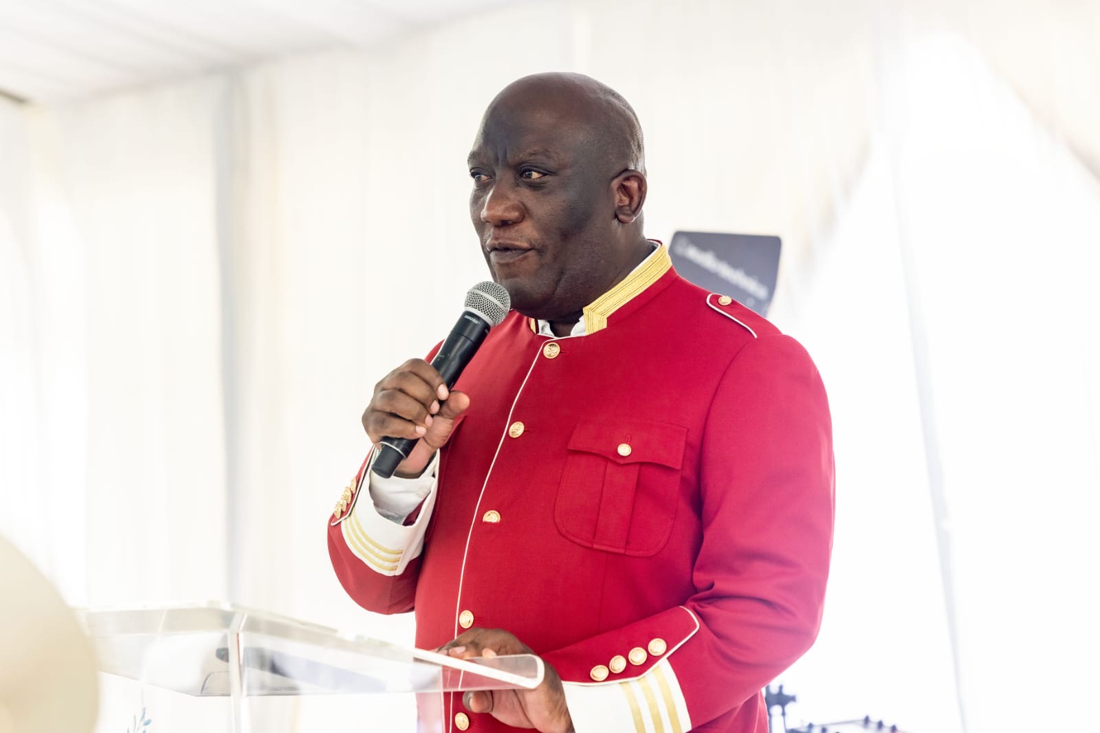 Bishop Mogodiri addressing a congregation from a glass pulpit