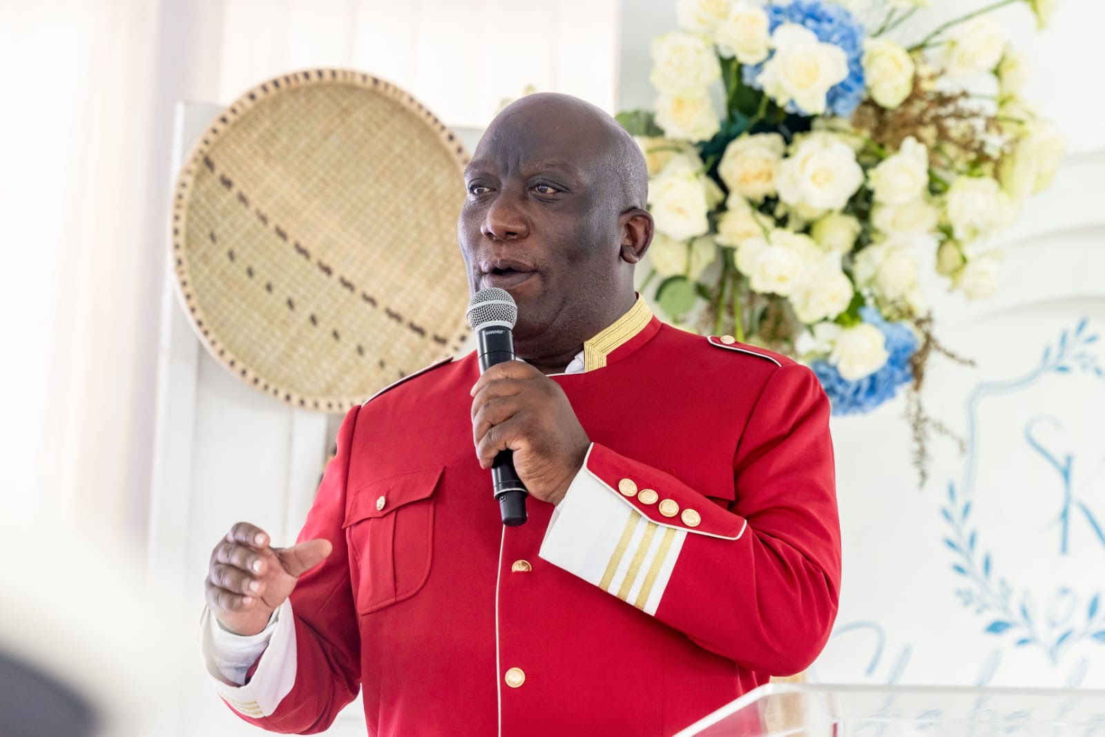 Bishop Mogodiri preaching into a microphone in a red ceremonial jacket